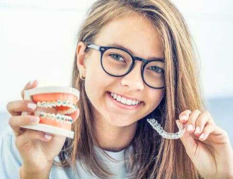 Dental invisible braces or silicone trainer in the hands of a young smiling girl. Orthodontic concept