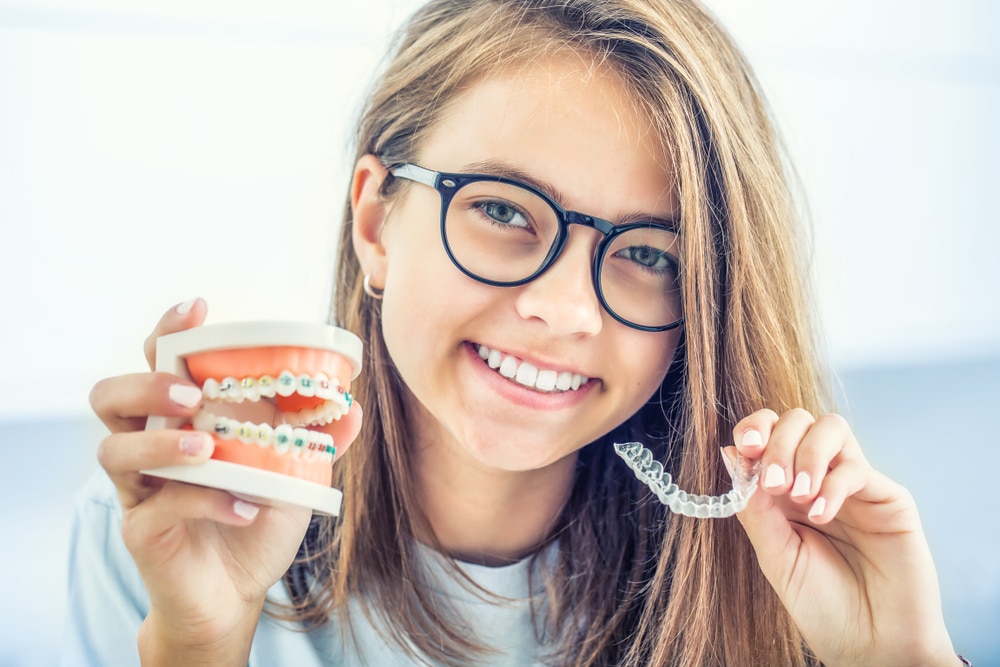 Dental invisible braces or silicone trainer in the hands of a young smiling girl. Orthodontic concept