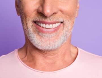 Cropped photo of pensioner old bristled man white beaming toothy smile wear pink t-shirt isolated purple color background