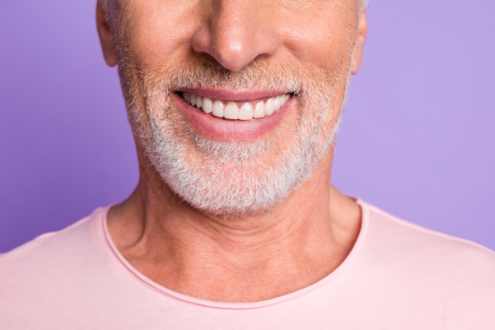 Cropped photo of pensioner old bristled man white beaming toothy smile wear pink t-shirt isolated purple color background