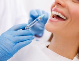 Detail of dentist applying local anesthetic to patient for numbing the pain before procedure. Focus on the drop on the top of the needle